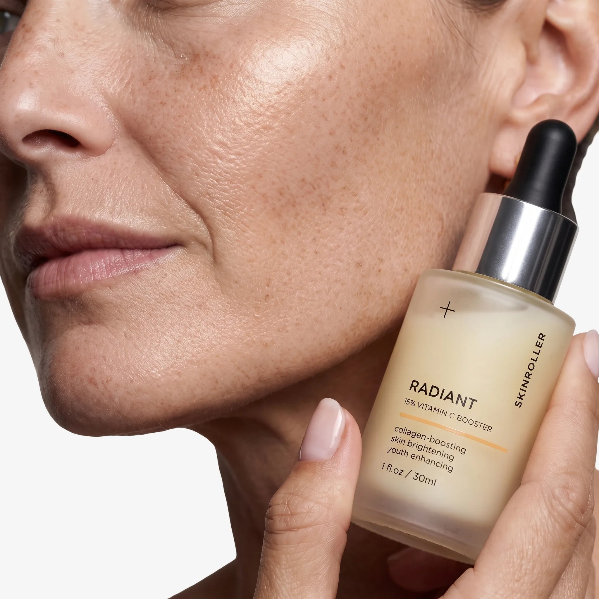 Image of Närbild på Radiant 15% Vitamin C Booster serum mot modellens kind