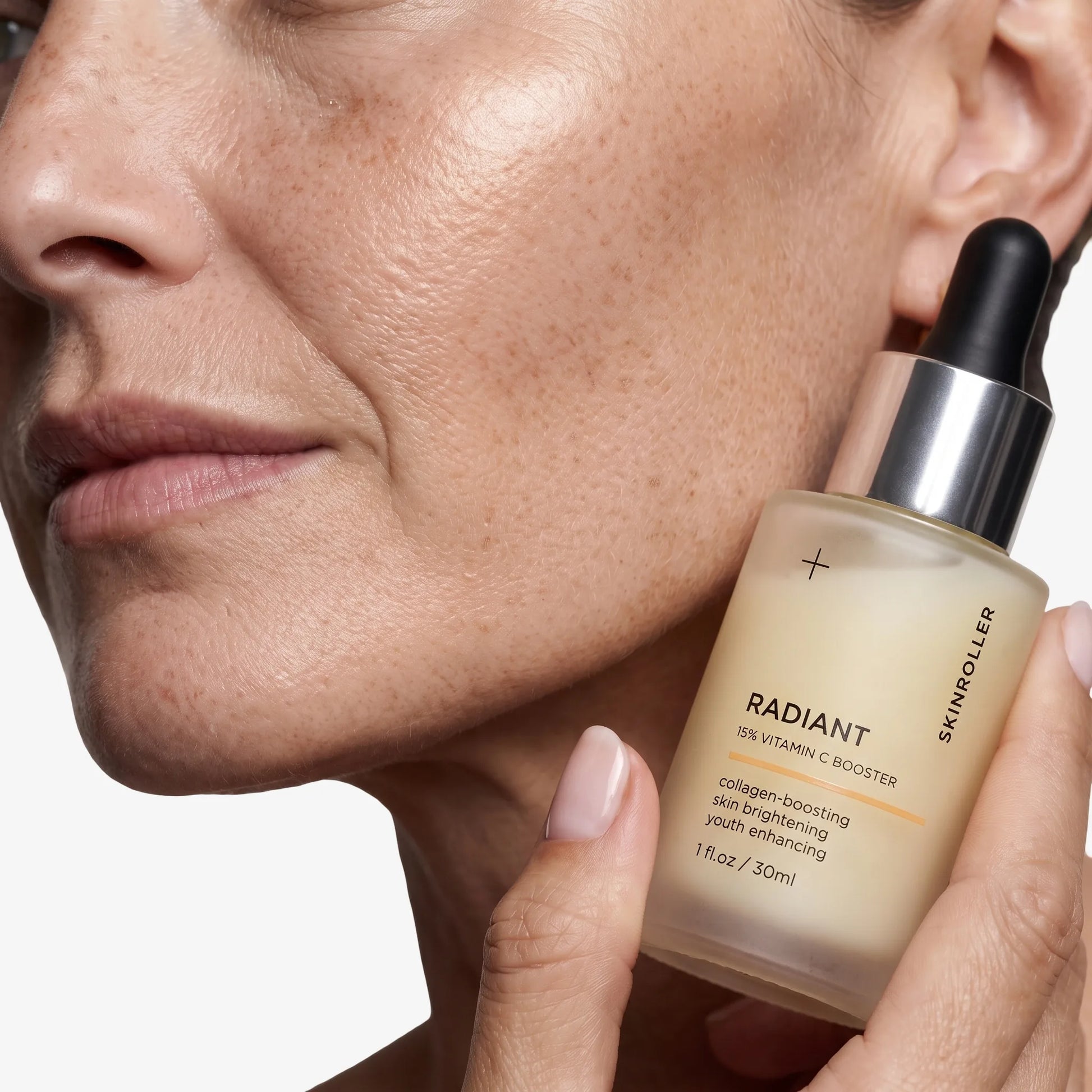 Närbild på Radiant 15% Vitamin C Booster serum mot modellens kind