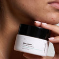 Modell håller Skinroller Brilliant Anti-Acne Cream 50ml mot ansiktet