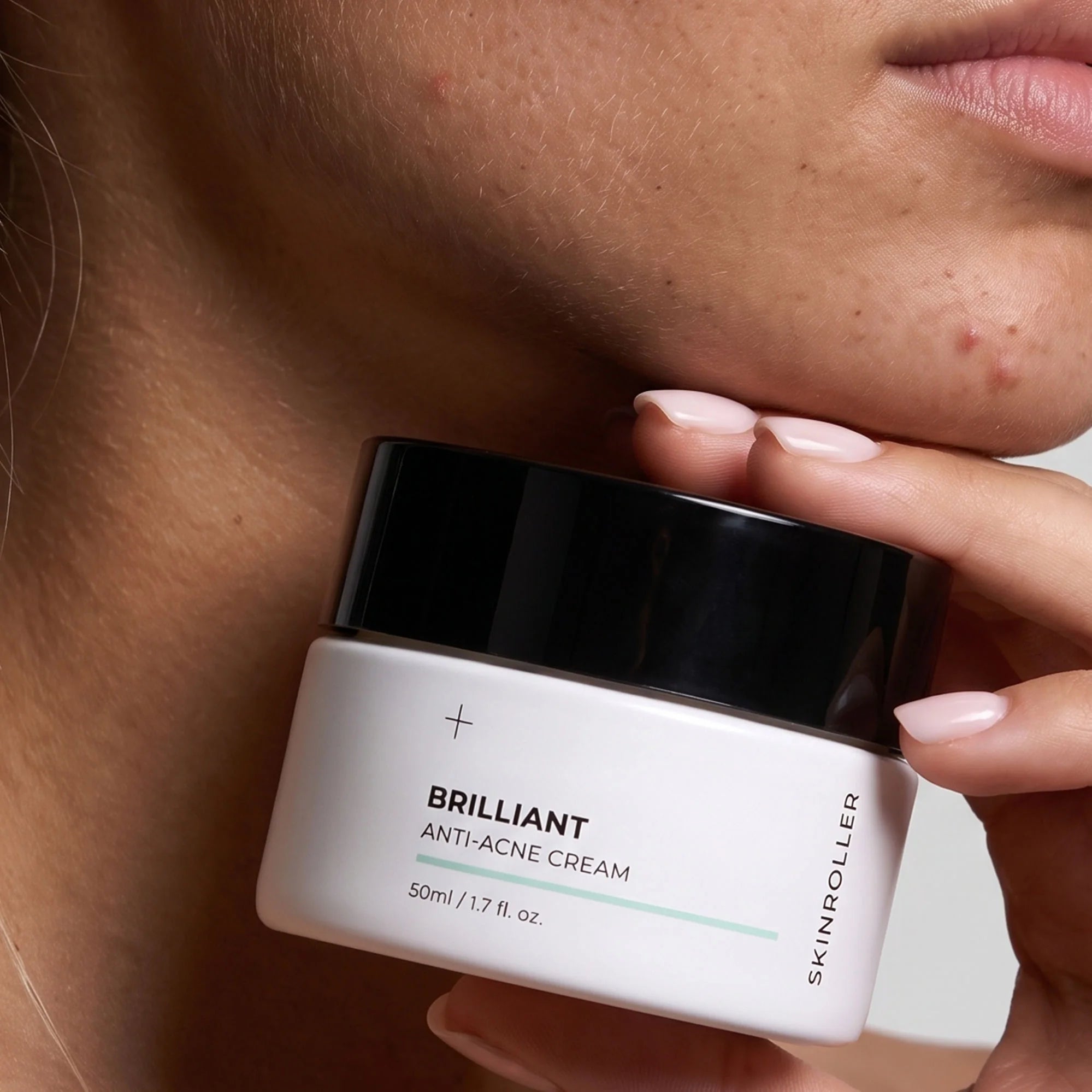 Image of Modell håller Skinroller Brilliant Anti-Acne Cream 50ml mot ansiktet