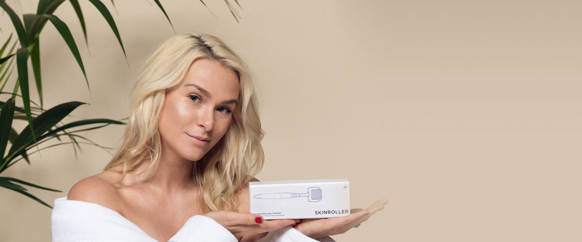 Kvinna i badrock håller upp en förpackning med Skinroller