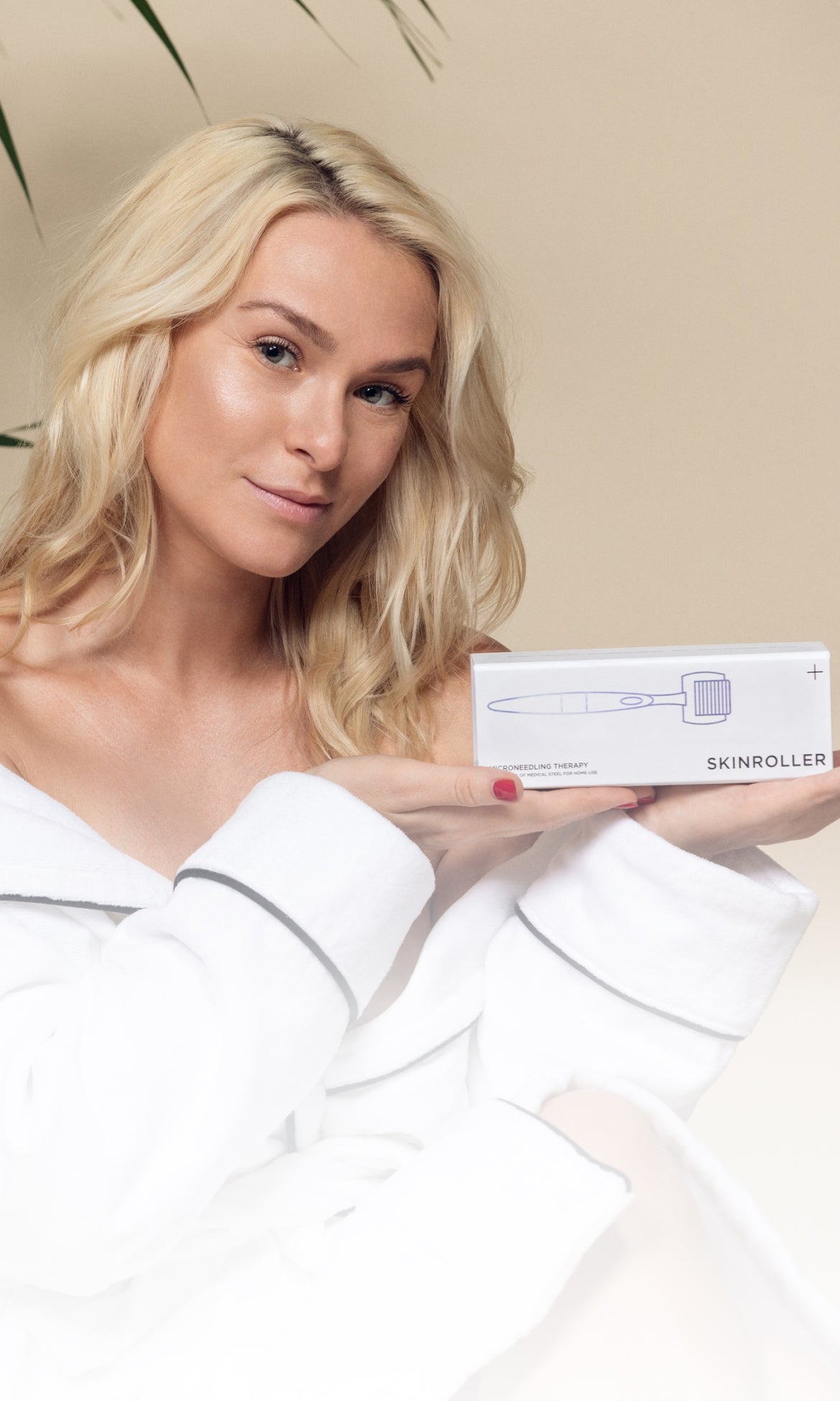 Kvinna i badrock håller upp en förpackning med Skinroller